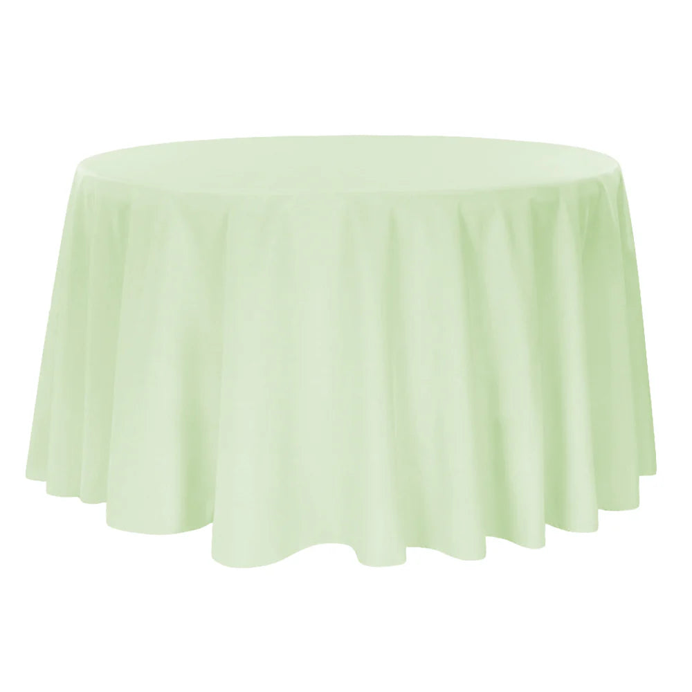 Round table covered with a sage green tablecloth on a white background