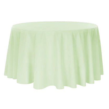 Round table covered with a sage green tablecloth on a white background